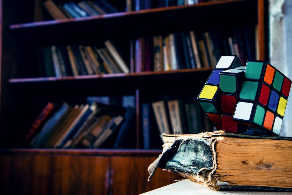 A vivid Rubik's cube resting on a worn book in a cozy library setting.